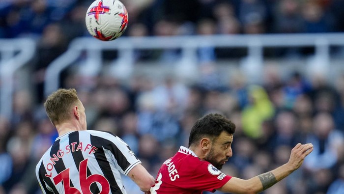 Newcastles Sean Longstaff, left, jumps for the ball with Manchester Uniteds Bruno Fernandes during the English Premier League soccer match between Newcastle United and Manchester United, at St. James Park stadium in Newcastle, England, Sunday, April 2, 2023. (AP Photo/Jon Super)