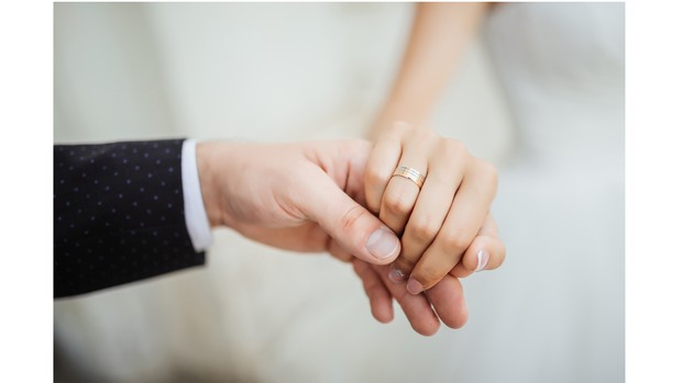 Foto ilustrasi pasangan pengantin yang saling memegang tangan.