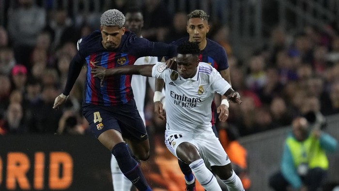 Barcelonas Ronald Araujo, left, challenges Real Madrids Vinicius Junior during the Spanish Copa del Rey semi final, second leg soccer match between Barcelona and Real Madrid at the Camp Nou stadium in Barcelona, Spain, Wednesday, April 5, 2023. (AP Photo/Joan Mateu Parra)