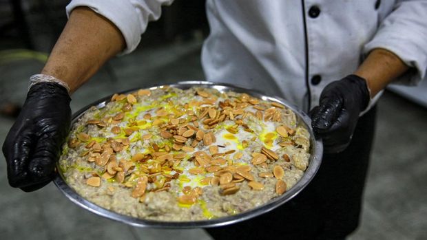 A cook walks with a tray of the traditional Jordanian dish 