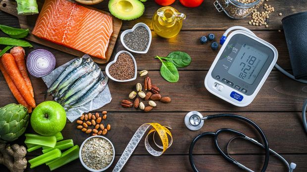 Healthy food for heart care: overhead view of healthy food rich in Omega-3 and antioxidants and a blood pressure monitor, tape measure and stethoscope shot on wooden table. The composition includes a salmon fillet, sardines, avocado, extra virgin olive oil, brown lentils, celery, artichoke blueberries, celery, carrots, brown lentils, asparagus, artichoke, broccoli, flax seeds, chia seeds and some nuts like almonds, pistachio and pecan. High resolution 42Mp studio digital capture taken with SONY A7rII and Zeiss Batis 40mm F2.0 CF lens