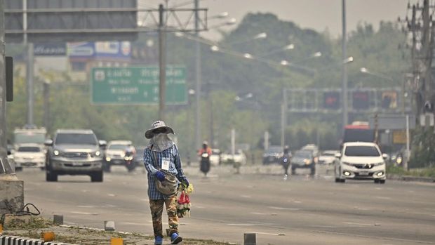 A vendor sells flowers on a highway amid high levels of air pollution in Chiang Mai on April 10, 2023. (Photo by Lillian SUWANRUMPHA / AFP)