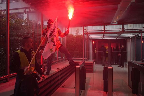 A protestors holds a lit flare outside the LVMH Moet Hennessy Louis Vuitton SE headquarters during a demonstration against pension reform in central Paris, France, on Thursday, April 13, 2023. French unions are holding strikes and protests on Thursday against President Emmanuel Macron's pension reform, seeking to maintain pressure on the government before a ruling on the law's constitutionality. Photographer: Nathan Laine/Bloomberg via Getty Images