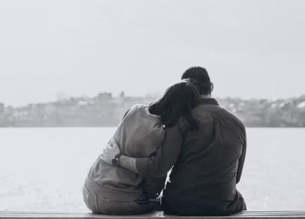 Perempuan dan laki-laki duduk di pinggir danau