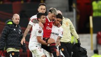 Melihat ekspresi kesakitan Lisandro Martinez, dua pemain Sevilla dengan gerak cepat langsung memapah bek MU itu. Foto: Getty Images/Matthew Ashton - AMA