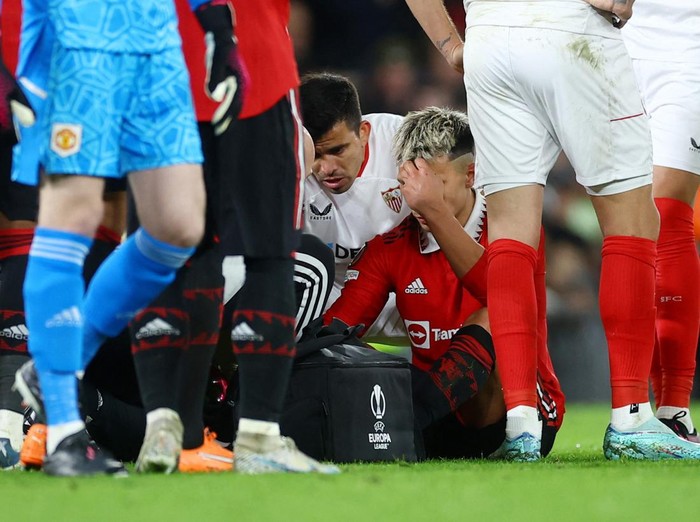 Soccer Football - Europa League - Quarter Final - First Leg - Manchester United v Sevilla - Old Trafford, Manchester, Britain - April 13, 2023  Manchester United's Lisandro Martinez receives medical attention after sustaining an injury as Sevilla's Marcos Acuna looks on Action Images via Reuters/Lee Smith