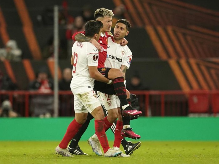 Sevilla's Marcos Acuna, left, and Sevilla's Gonzalo Montiel, right, help Manchester United's Lisandro Martinez off the pitch during the Europa League first leg quarterfinal soccer match between Manchester United and Sevilla at the Old Trafford stadium in Manchester, Thursday, April 13, 2023. (AP Photo/Dave Thompson)