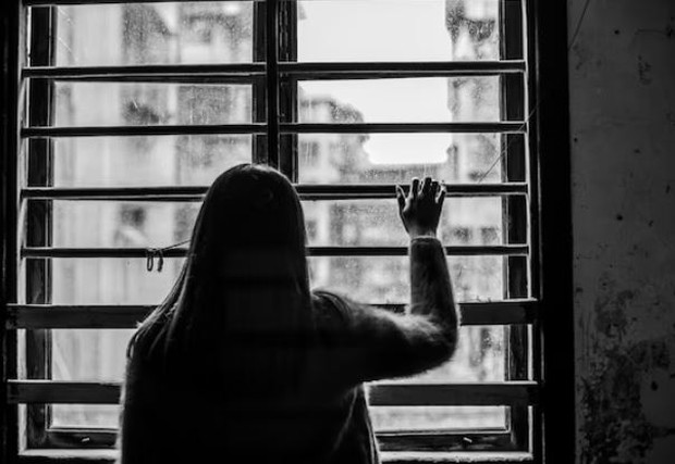 Perempuan sedang melihat ke luar jendela