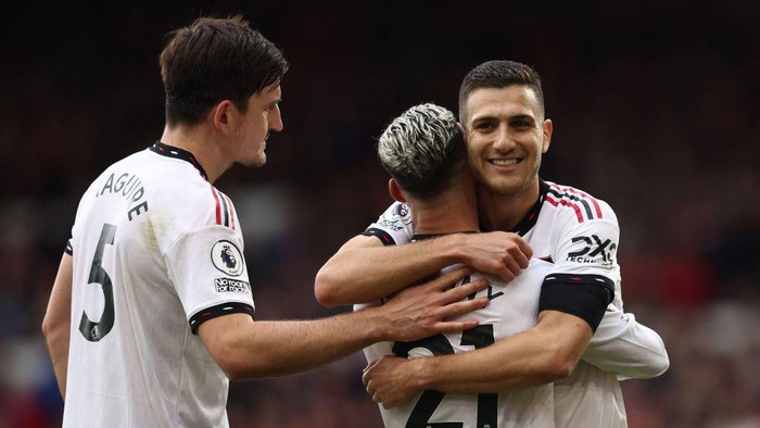 Manchester Uniteds Brazilian midfielder Antony (C) celebrates with Manchester Uniteds Portuguese defender Diogo Dalot (R) and Manchester Uniteds English defender Harry Maguire (L) after scoring the opening goal of the English Premier League football match between Nottingham Forest and Manchester United at The City Ground in Nottingham, central England, on April 16, 2023. (Photo by Darren Staples / AFP) / RESTRICTED TO EDITORIAL USE. No use with unauthorized audio, video, data, fixture lists, club/league logos or live services. Online in-match use limited to 120 images. An additional 40 images may be used in extra time. No video emulation. Social media in-match use limited to 120 images. An additional 40 images may be used in extra time. No use in betting publications, games or single club/league/player publications. /  (Photo by DARREN STAPLES/AFP via Getty Images)
