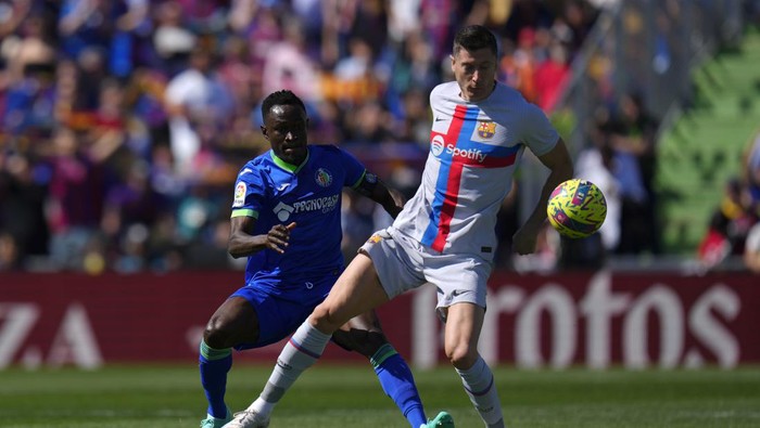 Barcelonas Robert Lewandowski, right, is challenged by Getafes Djene Dakonam during a Spanish La Liga soccer match between Getafe and FC Barcelona at the Coliseum Alfonso Perez stadium in Getafe, Spain, Sunday, April 16, 2023. (AP Photo/Manu Fernandez)