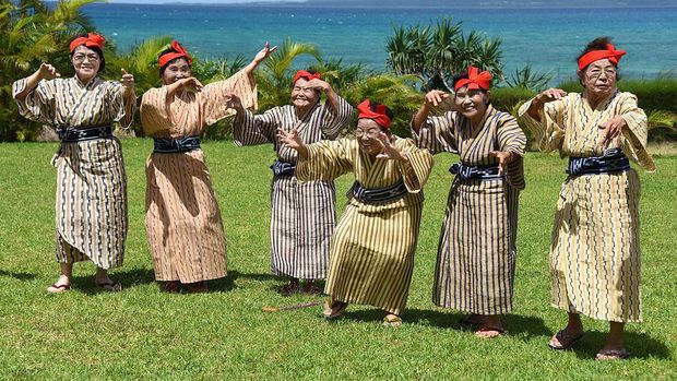 TO GO WITH AFP STORY BY ALASTAIR HIMMER In this picture taken on June 22, 2015, an elderly women troupe of singers and dancers from Kohama Island in Okinawa wearing traditional local costumes perform at a herb garden on Kohama Island, Okinawa Prefecture. They joke about knocking on heaven's door, but a Japanese 'girl band' named KBG84, with an average age of 84 have struck a blow for grannies everywhere by becoming pop idols. AFP PHOTO / Toru YAMANAKA (Photo credit should read TORU YAMANAKA/AFP via Getty Images)