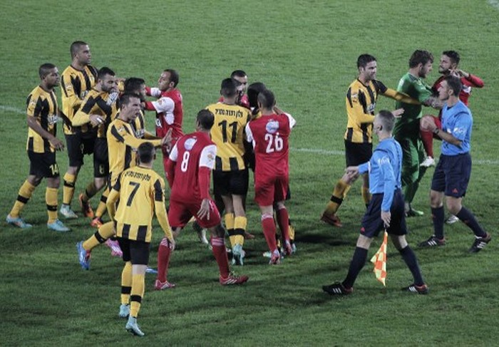 A football player from Bnei Sakhnin, the only Arab team in the Israeli Premier league, scuffles with a player from their mainly Jewish rivals Beitar Jerusalem at the Doha Stadium in the northern Arab-Israeli town of Sakhnin on November 23, 2014. Bnei Sakhnin beat Beitar Jerusalem 1-0 in a match that was under high police surveillance as tensions between Israeli Jews and Arabs remained high between the two clubs. AFP PHOTO / AHMAD GHARABLI (Photo by AHMAD GHARABLI / AFP)