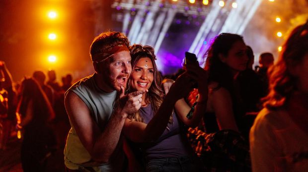 Two beautiful friends taking selfie with a samrtphone on a music festival