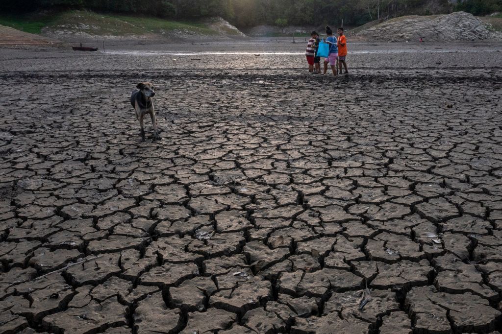 TOPSHOT - Aerial view showing a boy walking in the dried bed of Alhajuela Lake during the summer drought, in the Colon province, 50 km north of Panama City, on April 21, 2023. - The scarcity of rainfall due to global warming has forced the Panama Canal to reduce the draft of ships passing through the interoceanic waterway, in the midst of a water supply crisis that threatens the future of this maritime route. The Alhajuela lake, in the Colon province, 50 km north of Panama City, is one of the main lakes that supplies water to the locks of the Panama Canal and is at its lowest level of recent years. (Photo by Luis ACOSTA / AFP) (Photo by LUIS ACOSTA/AFP via Getty Images)