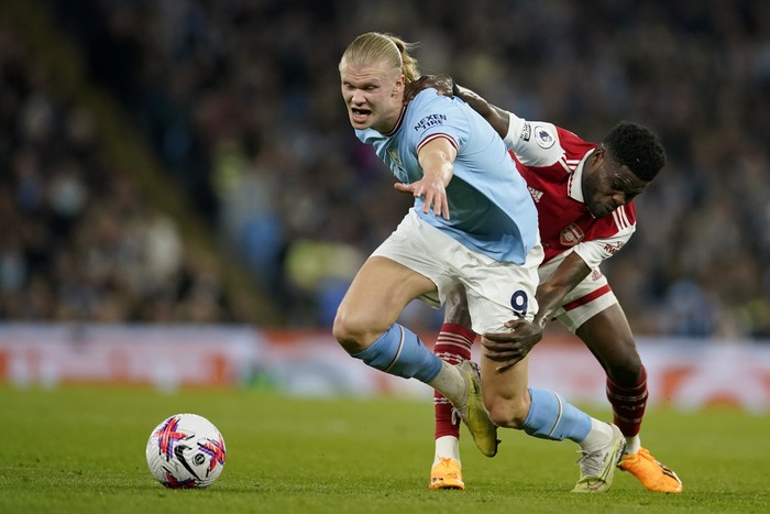 Arsenals Thomas Partey, right, tries to hold back Manchester Citys Erling Haaland during the English Premier League soccer match between Manchester City and Arsenal at Etihad stadium in Manchester, England, Wednesday, April 26, 2023. (AP Photo/Dave Thompson)