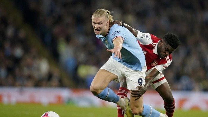 Arsenals Thomas Partey, right, tries to hold back Manchester Citys Erling Haaland during the English Premier League soccer match between Manchester City and Arsenal at Etihad stadium in Manchester, England, Wednesday, April 26, 2023. (AP Photo/Dave Thompson)