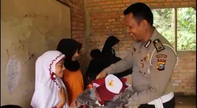 Aipda Ralon memberikan bantuan seragam kepada siswa di pedalaman Riau