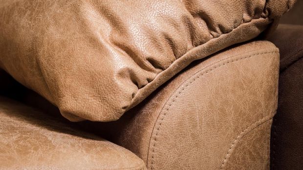 Close-up the Fragment of expensive beige leather sofa to indoors.