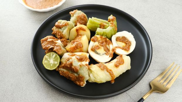 Siomay Bandung (Shumay) or steamed dumplings with boiled egg, tofu, potatoes and cabbage roll. Indonesian traditional street food with peanut sauce and soy sauce, served with green lime.