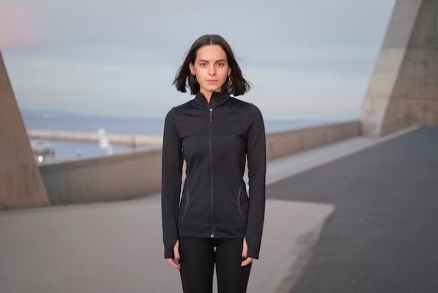 Perepuan memakai jaket hitam dengan wajah datar menatap kamera