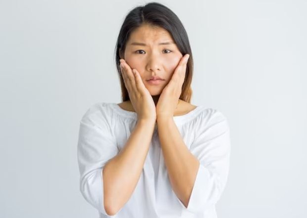 Perempuan sedang berpose memegang wajahnya