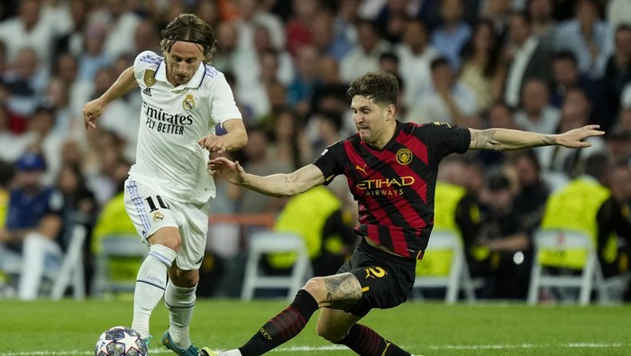 Real Madrids Luka Modric, left, duels for the ball with Manchester Citys John Stones during the Champions League semifinal first leg soccer match between Real Madrid and Manchester City at the Santiago Bernabeu stadium in Madrid, Spain, Tuesday, May 9, 2023. (AP Photo/Jose Breton)