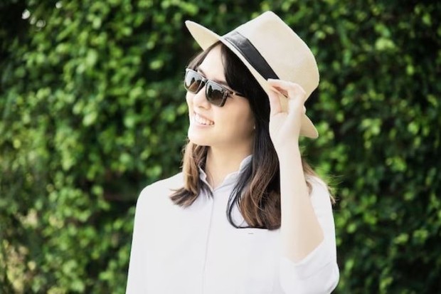 Perempuan mengenakan topi dan kacamata hitam