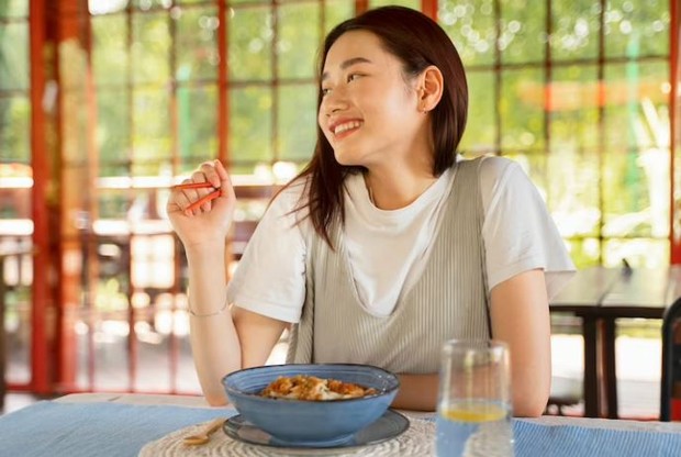Perempuan sedang makan sendirian di restoran