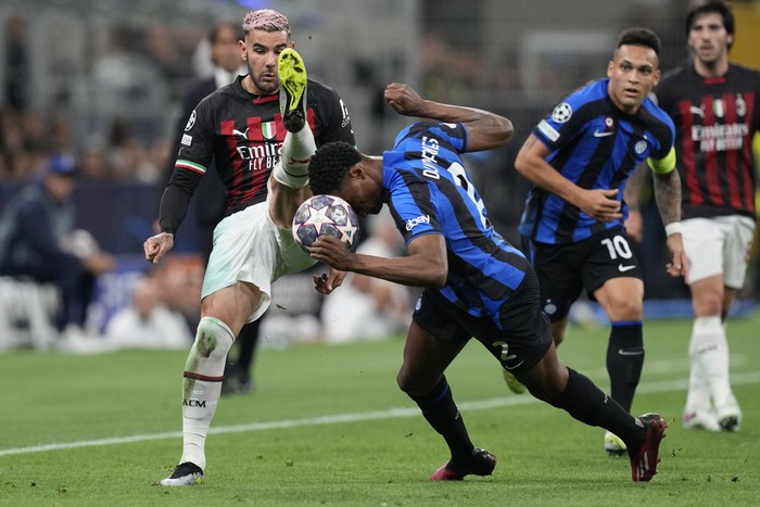 Inter Milans Denzel Dumfries, centre, is challenged by AC Milans Theo Hernandez during the Champions League semifinal second leg soccer match between Inter Milan and AC Milan at the San Siro stadium in Milan, Italy, Tuesday, May 16, 2023. (AP Photo/Antonio Calanni)