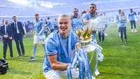 Erilng Haaland mengangkat trofi dan diguyur oleh Riyad Mahrez. (Foto: Getty Images/Michael Regan)