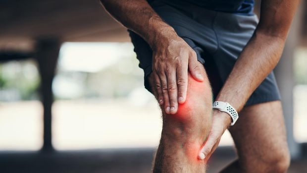Closeup shot of an unrecognizable man holding his knee in pain while exercising outdoors