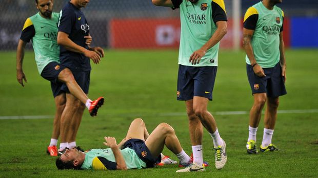 FC Barcelona football player Lionel Messi lies on the ground during a training session at the Bukit Jalil Stadium in the outskirts of Kuala Lumpur on August 9, 2013. Spanish club Barcelona will play a friendly with Malaysia XI on August 10 as part of the 2013 FC Barcelona Asia Tour. AFP PHOTO / MOHD RASFAN (Photo by MOHD RASFAN / AFP)