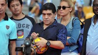 Maradona menandatangani bola sebelum membagikannya kepada penonton. (Foto: BAY ISMOYO/AFP via Getty Images)