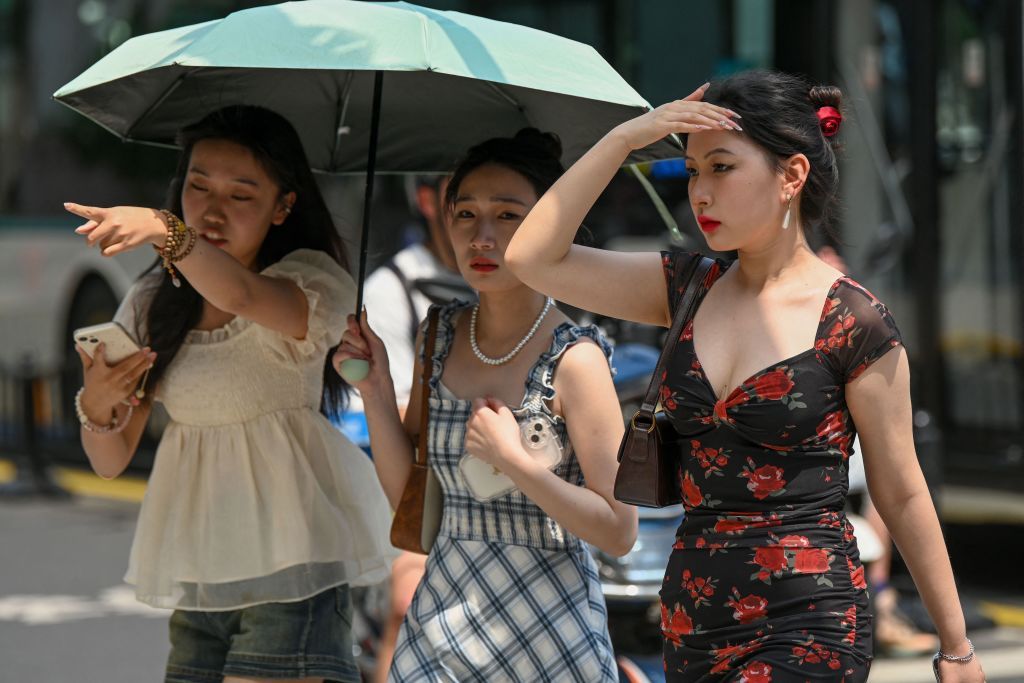 Women use an umbrella to shelter from the sun amid hot weather in Shanghai on May 29, 2023. Shanghai on May 29 recorded its hottest May day in 100 years, the city's meteorological service announced, shattering the previous high by a full degree. (Photo by AFP) / China OUT (Photo by STR/AFP via Getty Images)