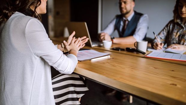 Man accompanied with two women sitting in board room and having business interview