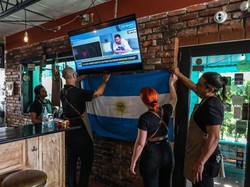 Karyawan restoran Argentina Fiorito menggantung bendera saat menonton pernyataan Lionel Messi di televisi, di Miami, Florida, Rabu (7/6/2023). Lionel Messi pada hari Rabu mengumumkan bergabung dengan klub Major League Soccer Inter Miami. Dia mengumumkannya sendiri.