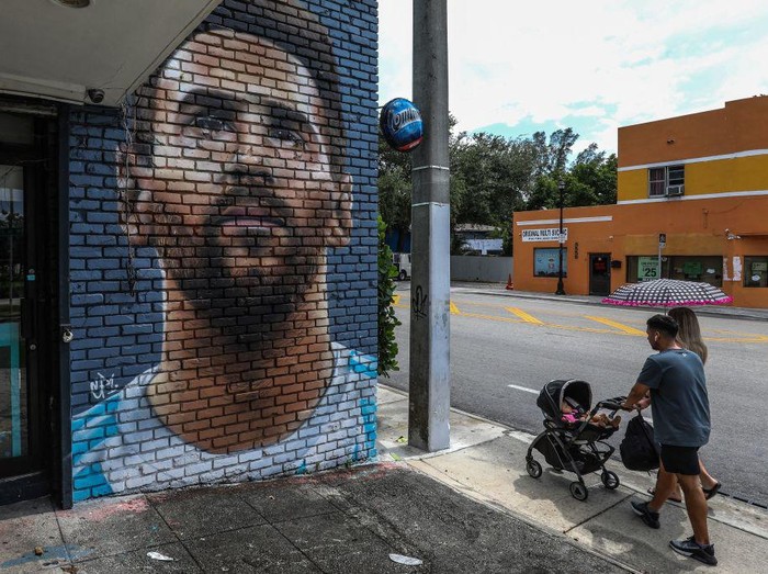 People walk in front of a mural depicting Argentine football player Lionel Messi in Miami on June 7, 2023. Lionel Messi on Wednesday announced he will sign for Major League Soccer side Inter Miami, choosing the United States as his next destination over a Barcelona reunion or blockbuster deal to play in Saudi Arabia. (Photo by Giorgio Viera / AFP) (Photo by GIORGIO VIERA/AFP via Getty Images)