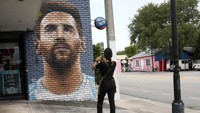 Jessica Ospina mengambil foto mural Lionel Messi di luar restoran Fiorito. AP/Lynne Sladky  