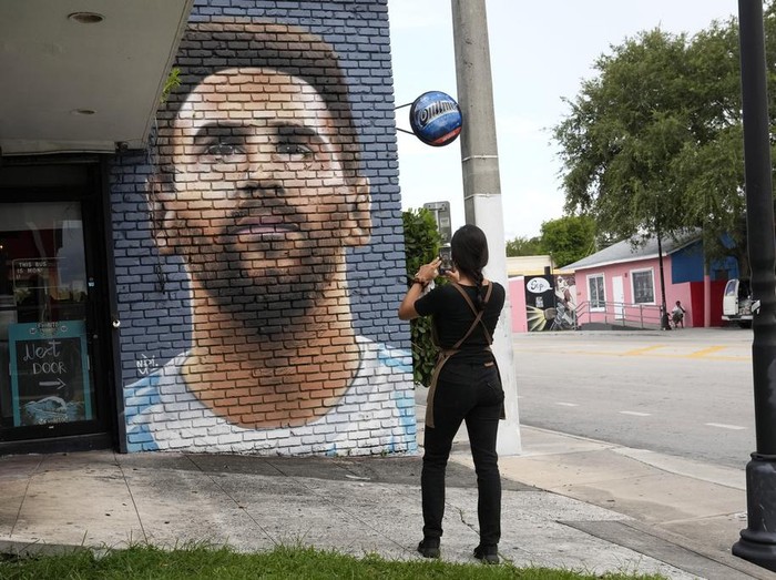 Jessica Ospina takes a photograph of a mural of Lionel Messi outside of the Fiorito restaurant, Wednesday, June 7, 2023, in Miami. The Argentine soccer star announced Wednesday he is joining the Inter Miami Major League Soccer team. (AP Photo/Lynne Sladky)