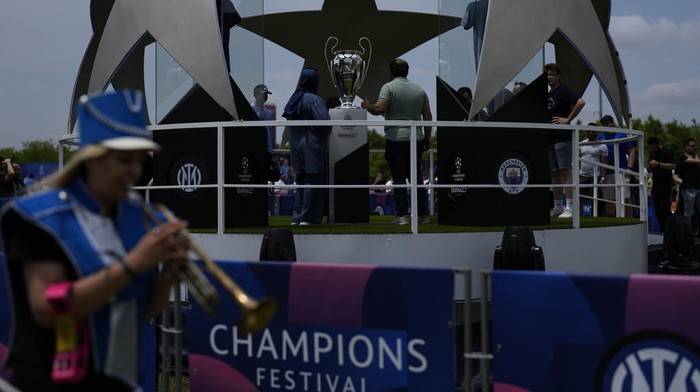 People take pictures next to a replica of the Champions League trophy in Istanbul, Turkey, Thursday, June 8, 2023. Manchester City will play Inter Milan in the final of the Champions League on Saturday June 10 in Istanbul.(AP Photo/Khalil Hamra)