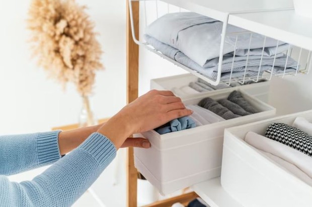 Tangan seseorang sedang merapikan baju di lemari