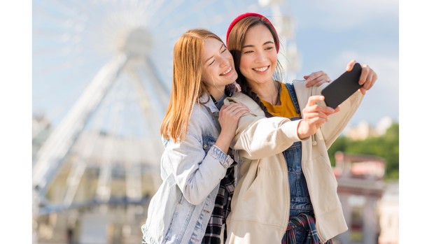 Ilustrasi dua orang perempuan yang tengah mengambil foto bersama.