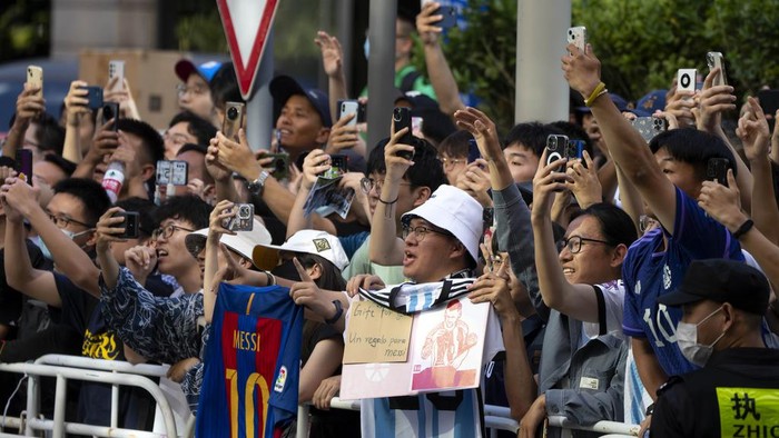 Chinese soccer fans cheer as they catch a glimpse of members of the Argentina national soccer team outside their hotel in Beijing, Monday, June 12, 2023. Argentina is scheduled to play Australia in a friendly match in China's capital on Thursday. (AP Photo/Mark Schiefelbein)