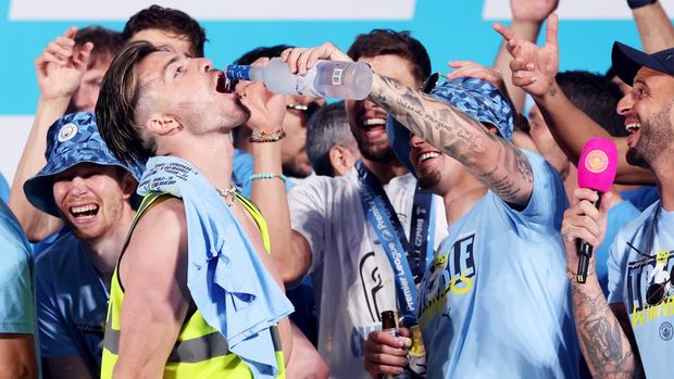 MANCHESTER, ENGLAND - JUNE 12: Kalvin Phillips of Manchester City pours Grey Goose into the mouth of Jack Grealish as they celebrate on stage in St Peter's Square during the Manchester City trophy parade on June 12, 2023 in Manchester, England. (Photo by Alex Livesey/Getty Images)