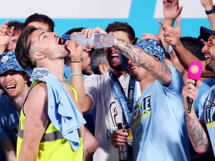 MANCHESTER, ENGLAND - JUNE 12: Kalvin Phillips of Manchester City pours Grey Goose into the mouth of Jack Grealish as they celebrate on stage in St Peter's Square during the Manchester City trophy parade on June 12, 2023 in Manchester, England. (Photo by Alex Livesey/Getty Images)