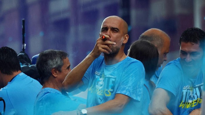 Soccer Football - Manchester City Victory Parade - Manchester, Britain - June 12, 2023 Manchester City manager Pep Guardiola is pictured smoking a cigar during the parade REUTERS/Molly Darlington