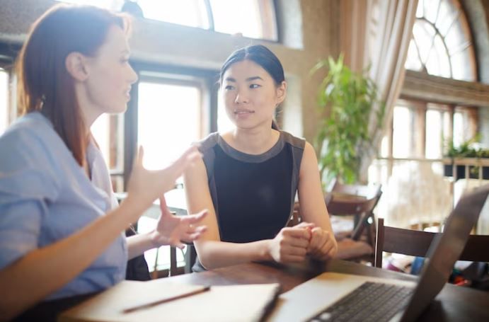 Dua perempuan sedang mengobrol