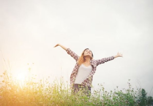 Perempuan sedang merentangkan tangan menikmati alam