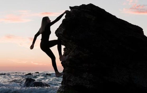 Siluet perempuan sedang panjat tebing