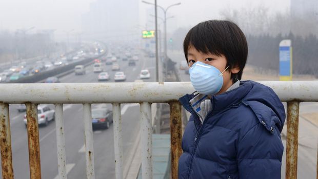 Asian child protects himself against air pollution by wearing mouth mask